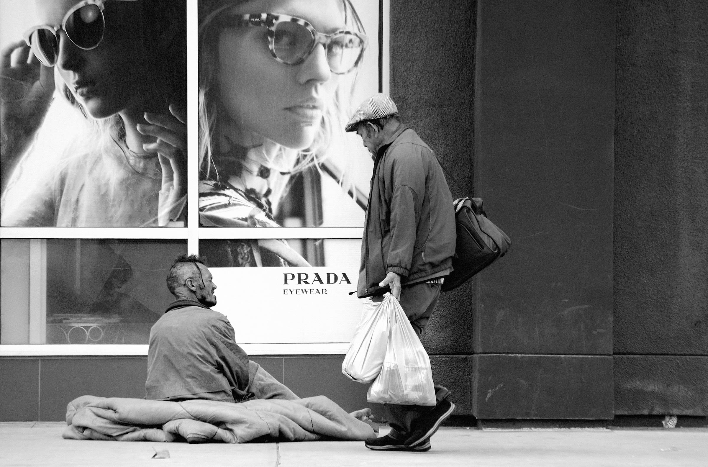 grayscale photo of a man and dog lying on sidewalk